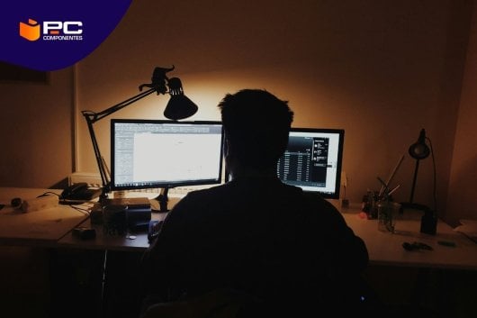 Un chico trabaja en su escritorio con dos monitores de ordenador