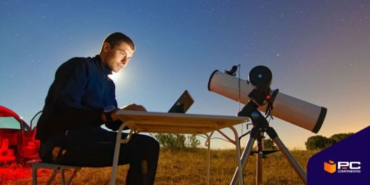 Un chico revisa en el campo junto a un telescopio astronómico