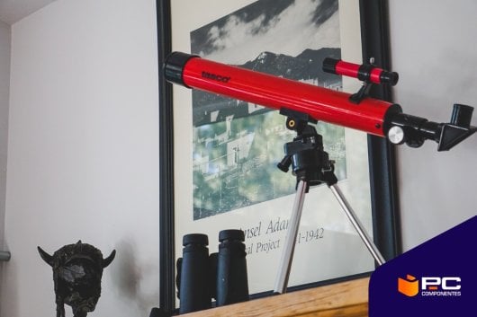 Un telescopio rojo con una pared blanca de fondo