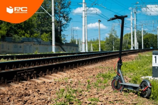 Un patinete eléctrico de la marca Xiaomi junto a unas vías de tren
