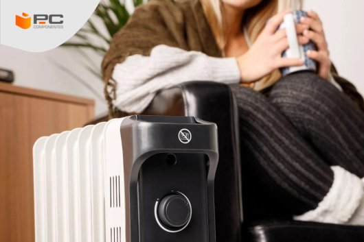 Una chica se calienta junto a un radiador eléctrico de aceite