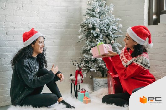 Dos mujeres vestidas de navidad con uno de los mejores regalos para mujer en la mano
